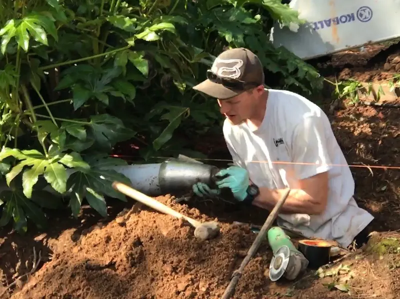 Technician setting a new drain line in a garden bed