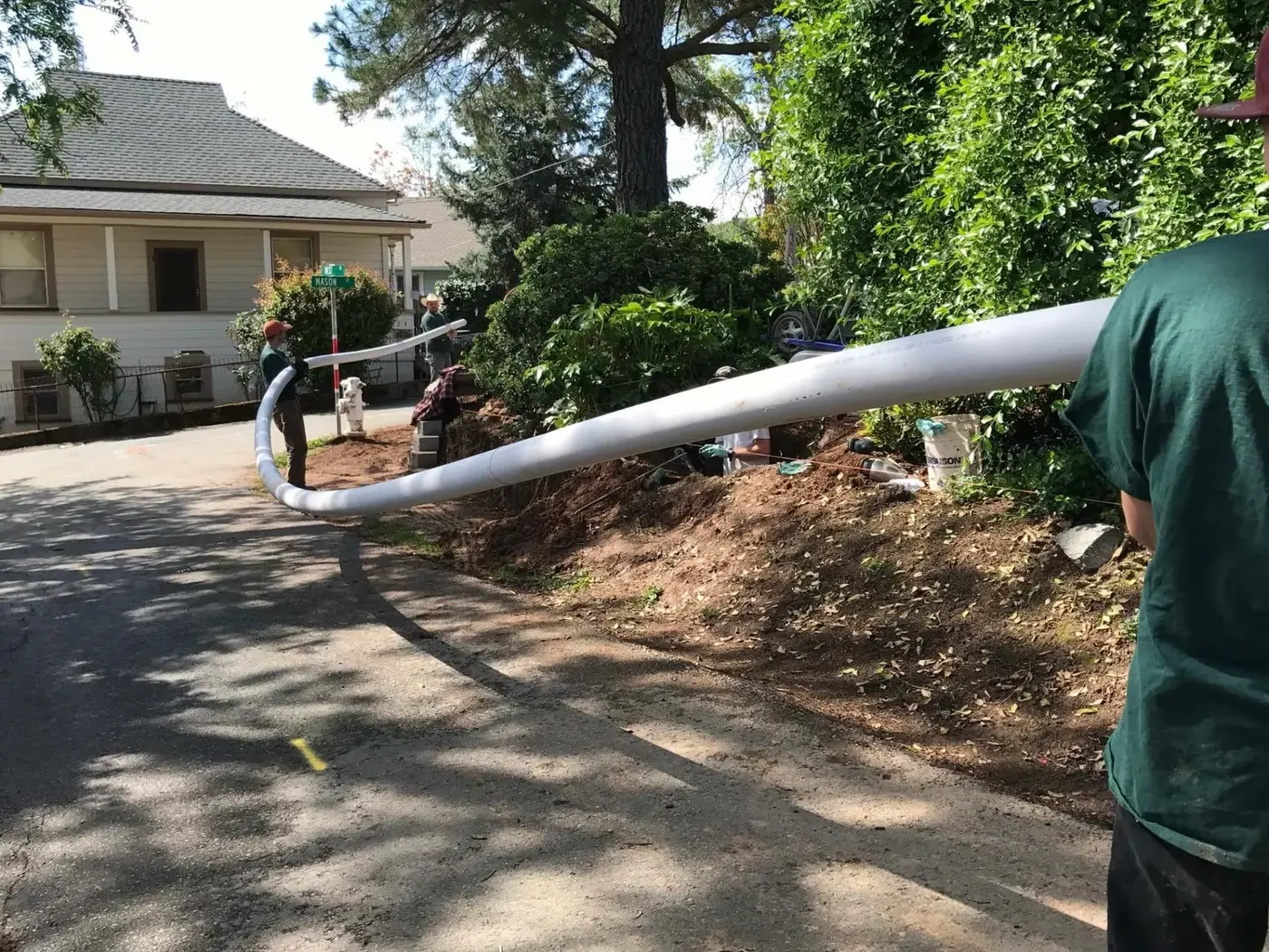 Amador Plumbing crew carrying a new sewer pipe down a Sutter Creek street